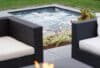 Hot Tub Maintenance | Spa with roaring water with patio nearby with plants and outdoor furniture | Immerspa - The Best Fiberglass Inground Spas, Hot Tubs, & Pools